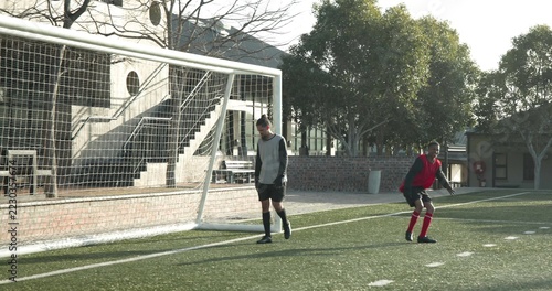 Soccer player scoring goal while goalkeeper diving on outdoor field