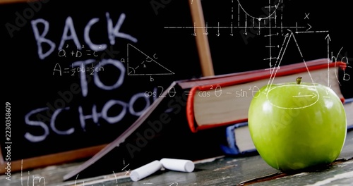 Sitting bright green apple on desk in classroom, with chalk, blackboard, math diagrams, copy space
