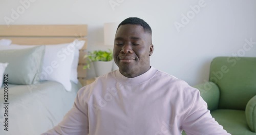 African American man starting prayer pose opening arms placing hands chest belly by bed centering