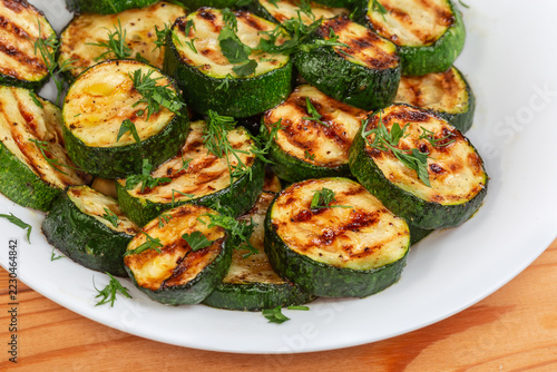 Grilled circles of green zucchini on plate, fragment close-up