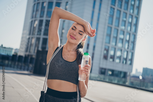 Photo of sportive lady aerobics training sweat forehead hold drink bottle warm summer weather wear crop top outside