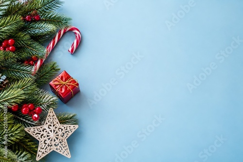 Fir Branches and Candy Cane Beside Pale Blue Christmas Copy Space