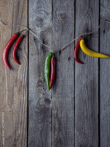 Obraz na plátně Vibrant chilies dangle against worn wooden planks