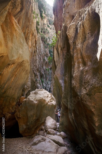 Hiker exploring the towering limestone gorge of Torrent de Pareis in Mallorca, Spain