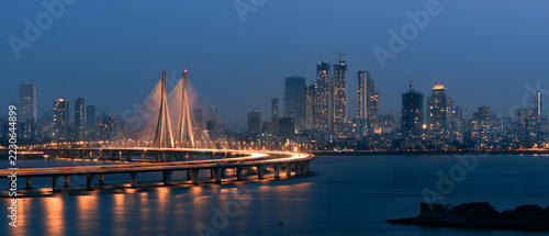 At evening, Mumbai's skyline gleams with the illuminated Bandra-Worli Sea Link bridge, while city lights reflect on the water, forming a modern cityscape of an Indian metropolis.