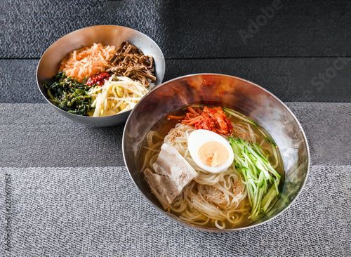 Fotografie Traditional Korean Cold Noodles Naengmyeon with Meat and Banchan Side Dishes on