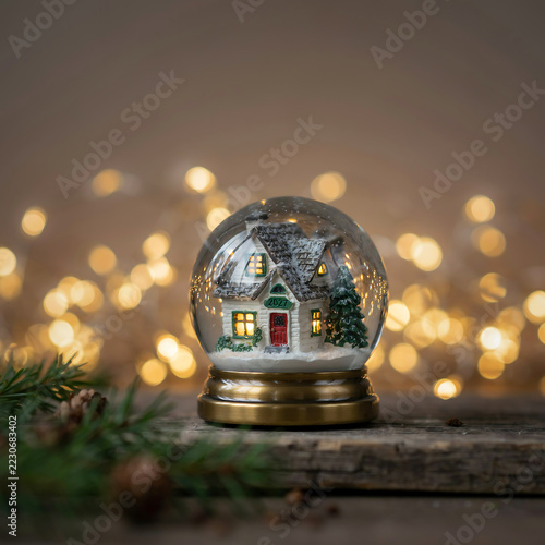 New Year 2027 Snow Globe with Miniature House on Rustic Wood and Warm Bokeh Lights