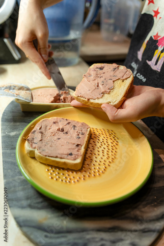 Hands spreading liver pate on toasted bread slices for a quick and delicious snack