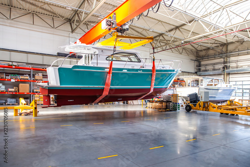 Bright orange crane lifts sleek blue boat