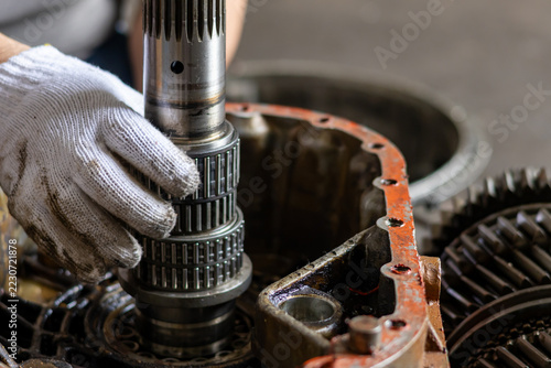 Mechanic aligning needle bearing on transmission shaft during overhaul.