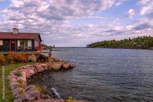 Rocky shoreline of Killarney Channel in Ontario, looking towards Georgian Bay at sunset, with a charming lakeside cabin and scenic sky.