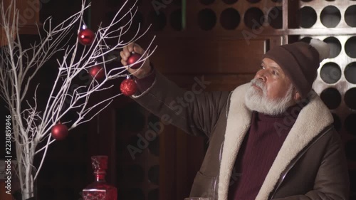 Senior man in winter clothes sits at bar looking at Christmas decor
