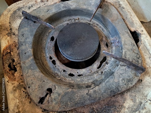 Old rusty broken gas stove burner with rusted metal surface and holes. Perfect stock photo for articles about gas leak risks, home safety hazards, or kitchen appliance maintenance.