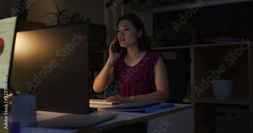 Image of asian businesswoman using smartphone, working late in office