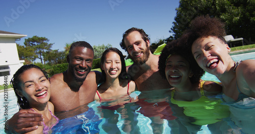 Diverse group of friends having fun taking a selfie in swimming pool