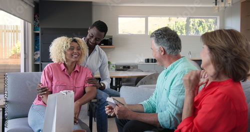 Celebrating pregnancy, Senior couple enjoying conversation with friends at home, sharing joyful mome