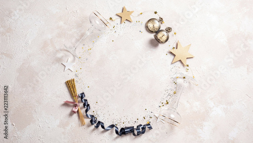 Elegant New Year's Eve Flat Lay with Crystal Champagne Glasses, Vintage Brass Pocket Watch Near Midnight, Gold Star Confetti and Navy Ribbon on Blush Textured Background