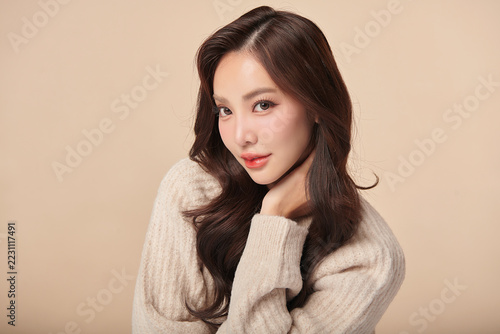 A beautiful young Asian woman with clean, fresh skin against a beige background. Skincare, facial treatment, cosmetology, beauty, and spa. An elegant portrait of an Asian woman.