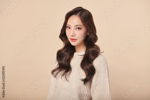 A beautiful young Asian woman with clean, fresh skin against a beige background. Skincare, facial treatment, cosmetology, beauty, and spa. An elegant portrait of an Asian woman.
