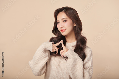 A beautiful young Asian woman with clean, fresh skin against a beige background. Skincare, facial treatment, cosmetology, beauty, and spa. An elegant portrait of an Asian woman.