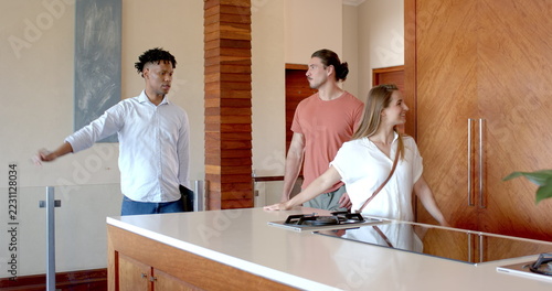 At party, Chatting casually, friends in modern kitchen having relaxed conversation together