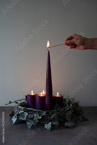Hand lighting tall purple Advent candle, the traditional Christmas preparation.