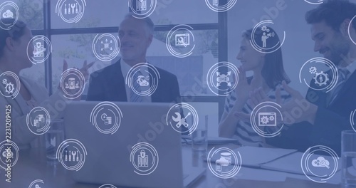 Discussing business team wearing officewear gesturing at meeting table with laptop digital overlay