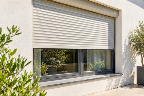 Exterior roller shutter partly lowered over a sunny window