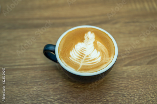 Cup of hot coffee latte with latte art on wooden table