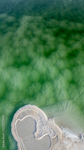 aerial top down nadir view of white salt formation in emerald turquoise dead sea water