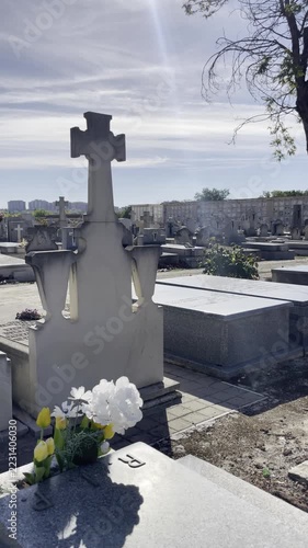 Tumba de muerto y flores en cementerio camposanto rip halloween cemetery día de todos los santos sepultura, cruz gravestone, entierro y nicho dep con cielo azul y reflejo de lente