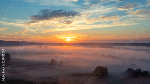 Beautiful aerial shot of a forest on a hill with beautiful mist in the distance shot at sunrise