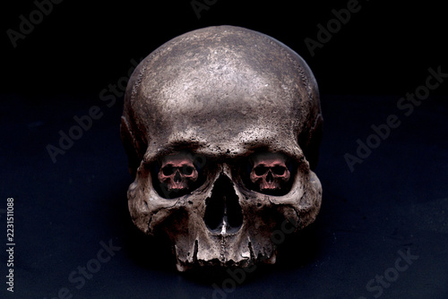 Surreal Human Skull with Miniature Skulls Inside Eye Sockets on Dark Background