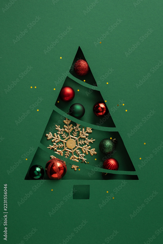 Obraz premium Christmas tree vertical paper cutout with baubles and snowflake on a vertical green festive background