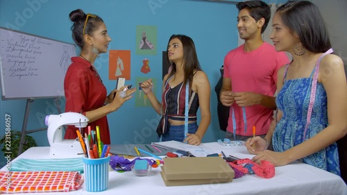 College students engaged in a fashion designing workshop - learning concept. Female fashion lecturer taking a fashion studies workshop at her atelier workplace - the concept of professional diploma...