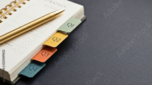 Spiral planner with quarterly year index tabs on desk for business strategy, quarterly planning and project organization