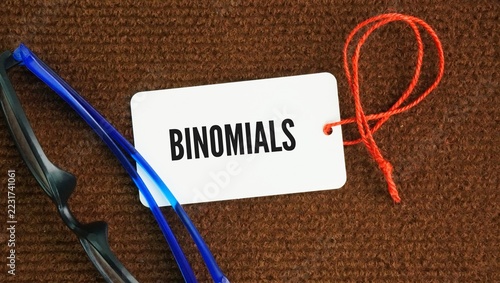 Fotografie Glasses and paper tags with the word binomial has two primary meanings depending on whether you are studying algebra, linguistics, or biology