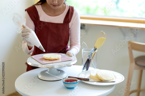Young Girl Decorating Homemade Cookie with Frosting on Cake Stand in Bright Kitchen