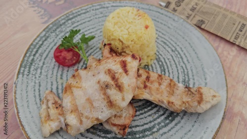 Grilled chicken breast serving with yellow rice and tomato
