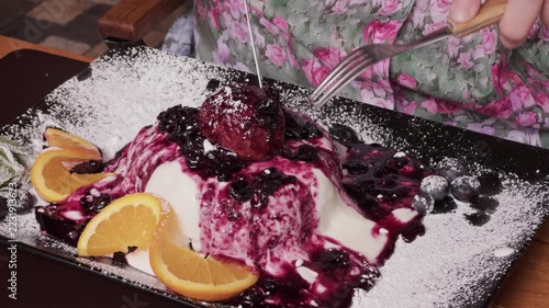 Eating sweet dessert with cream and blueberry sauce