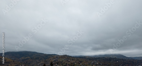 Canvas Print Overcast sky and low clouds over dark mountain hills and autumn forests