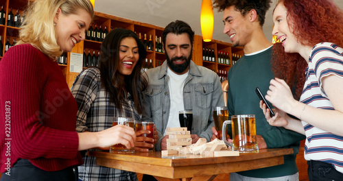 A diverse group of young adults is enjoying a social game at a bar, with copy space
