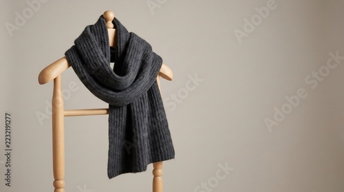 Charcoal grey knitted scarf hanging on wooden valet stand, minimalist winter apparel, warm wool knitwear accessory, elegant autumn fashion still life.