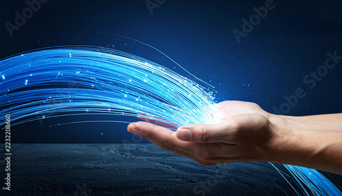 Abstract Technology in Hand: A person's hand holds a flowing stream of glowing blue light, representing data, connectivity, and technological advancement against a dark, futuristic backdrop.