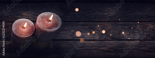 Two burning candles with magical bokeh lights on old wooden table. Horizontal top view photography with copy space. Perfect for special moments.
