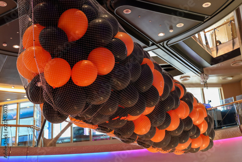 Halloween balloon drop net with orange and black balloons suspended from a ceiling.