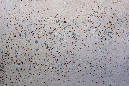 Full-frame texture of an exposed aggregate concrete surface displaying a speckling of multi-colored stone chips embedded in smooth gray grey cement