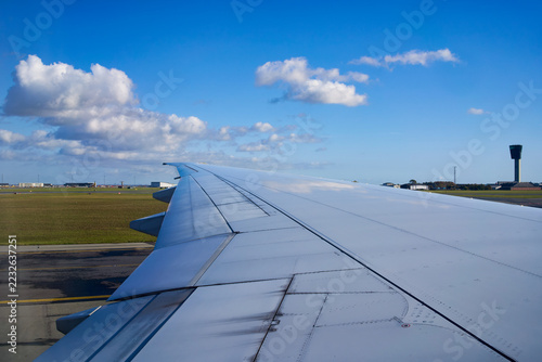 View from the airplane window while airplan taking off on runway to sky for travel to destination and the airplane wing.