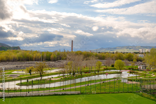 Fotografie Riverside park with winding ponds and paths below a dramatic sky in Gori, Georgi