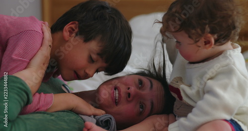 Fotografie Toddler pulls mother's hair repeatedly while older brother competes for attentio